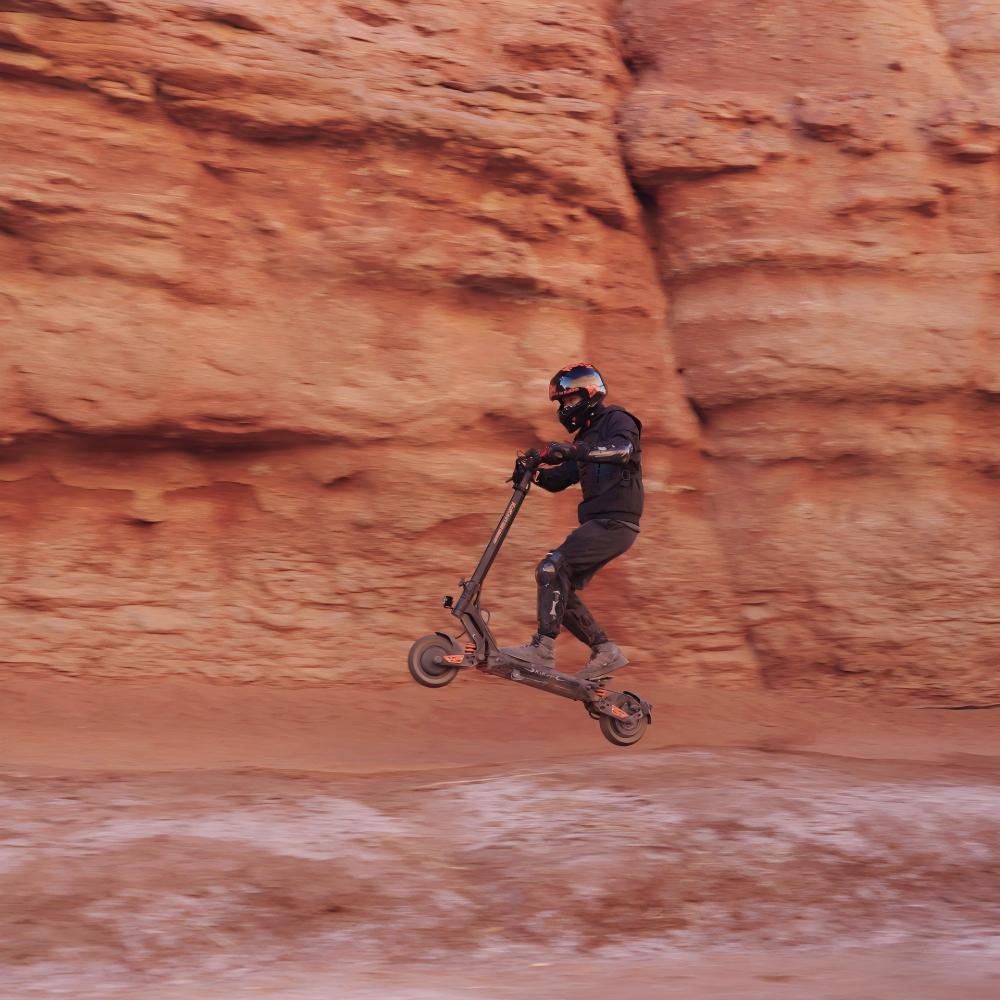 KuKirin G2 Master all-terrain scooter catching air over a canyon jump.