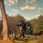 Riding the KuKirin G2 Max off-road electric scooter on a forest trail.