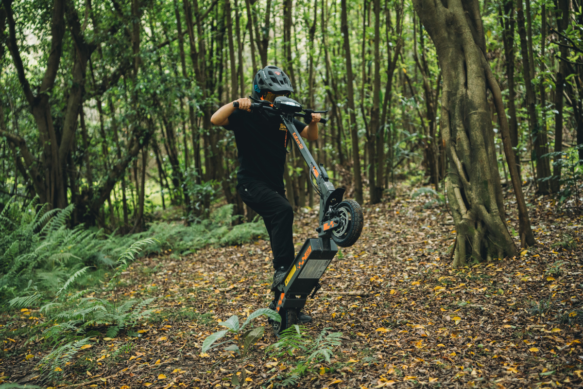 KuKirin G2 performing a wheelie on a forest dirt trail