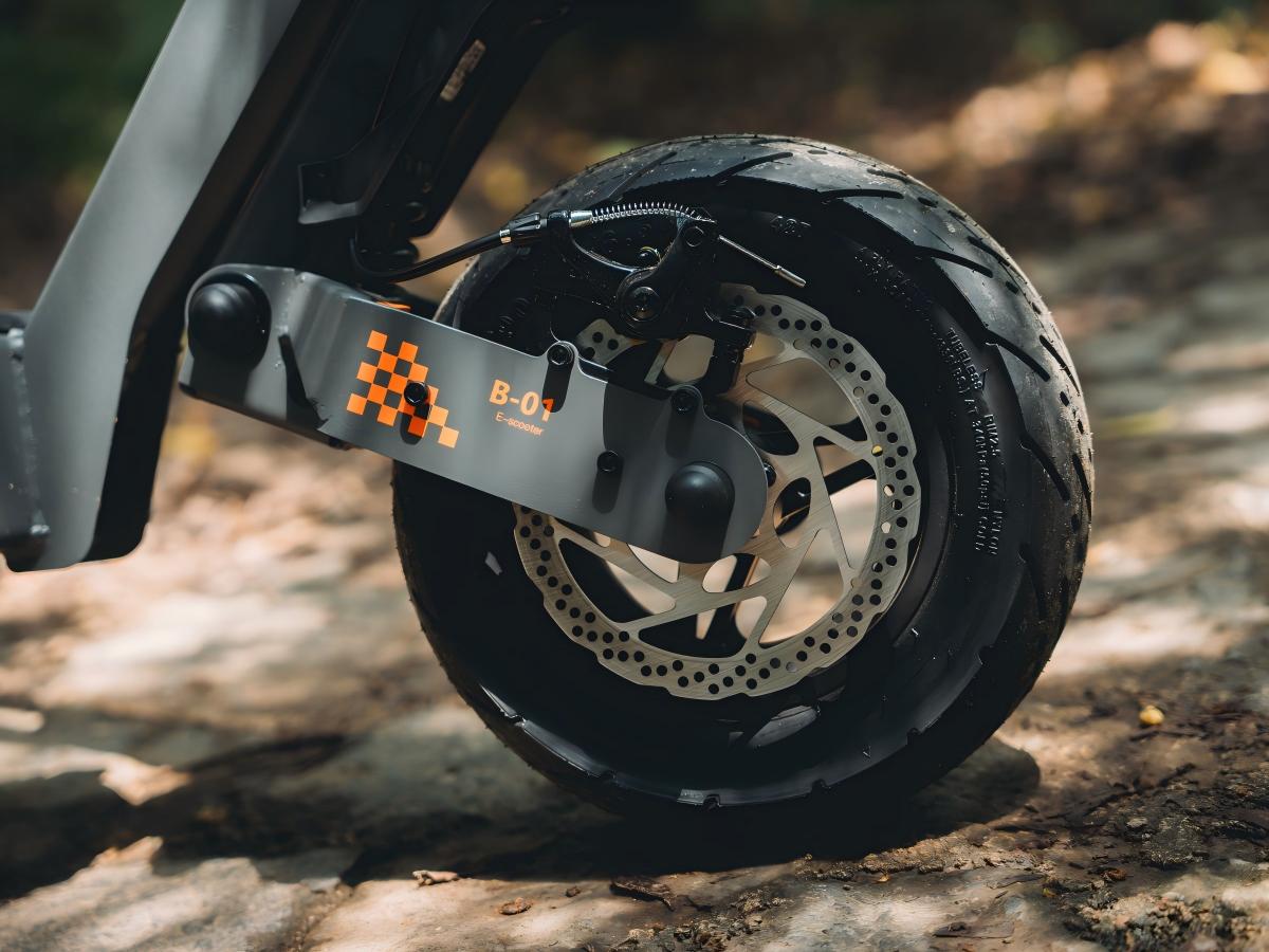 Close-up of the KuKirin G4 front wheel featuring a high-performance disc brake and rugged 11 inch off-road tire tread