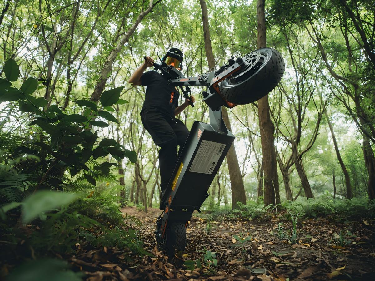 KuKirin G4 electric scooter performing a wheelie on a forest trail