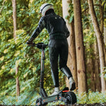 Back view of a rider on a KuKirin G4 through a wooded path