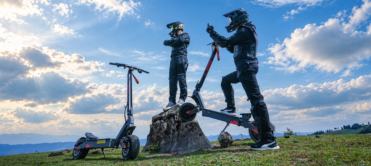 KuKirin G4 Ultra dual-motor electric scooters parked on a scenic mountain hill with riders under a blue sky